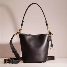 Black Coach Bag That Can Be Used As A Crossbody Or Shoulder Bag. Glovetanned Leather Inside Zip Pocket Snap Closure, Fabric Lining Detachable Handle With 8" Drop Detachable Strap With 21 1/2" Drop For Shoulder Or Crossbody Wear Four Protective Feet At Base 6" (L) X 7 1/4" (H) X 4" (W) Coach Bucket Shoulder Bag With Branded Hardware, Classic Bucket Bag With Branded Hardware, Luxury Coach Bucket Bag With Detachable Handle, Luxury Coach Bucket Bag With Detachable Strap, Elegant Coach Crossbody Bucket Bag, Coach Formal Bucket Bag With Detachable Handle, Elegant Coach Bucket Bag With Adjustable Strap, Classic Black Bucket Bag With Branded Hardware, Luxury Coach Bucket Bag