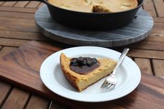 a piece of cake on a plate with a fork next to it and a skillet in the background