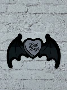 a bat shaped sign on the side of a white brick wall that says bat boy