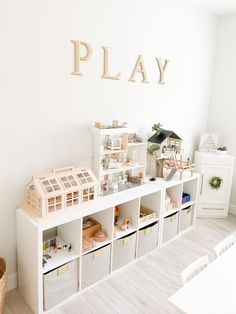 a play room with toy houses and toys on top of the shelves in front of it