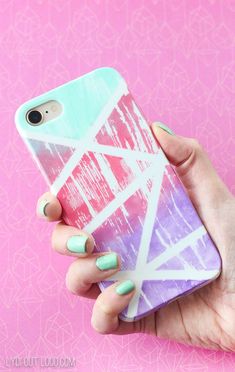 a woman holding up her phone case in front of pink background