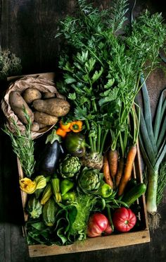 a box filled with lots of different types of veggies on top of a wooden table