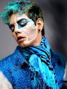 a man with blue and white face paint on his face, wearing a scarf around his neck