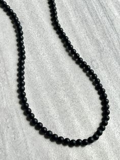 Men's beaded necklace features: ~ 6mm, 8mm or 10mm Matte Onyx beads ~ Choose your length; 20", 22", 24", 26", 28", 30" ~ Clasp-free, made with clear stretchy cord to easily put on and take off ~ Comes packaged in a re-usable microfiber pouch ~ Use the sizing guide found in the photo gallery to choose the length that's right for you Classic Beaded Necklaces With Round Beads, Classic Beaded Necklaces With Round Beads For Everyday, Classic Single Strand Beaded Necklaces, Classic Single Strand Beaded Necklace For Everyday, Classic Adjustable Necklace With 8mm Beads, Classic Adjustable Single Strand Beaded Necklace, Classic Single Strand Beaded Necklace, Black Necklaces With Round Beads For Everyday, Classic Black Beaded Necklaces