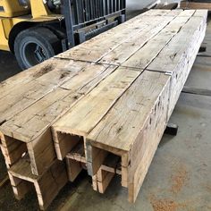 large wooden planks are stacked on top of each other in front of a forklift