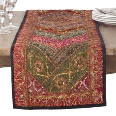 the table runner is decorated with an intricately designed design and has wine glasses on it