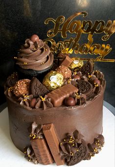 a birthday cake with chocolate frosting and candies on the top that says happy birthday