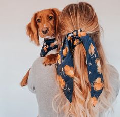 a woman with long blonde hair wearing a bandana and holding a dog on her back