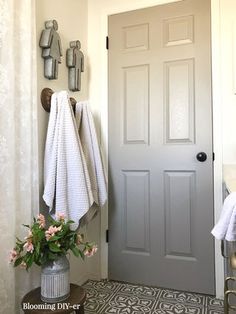 a bathroom with a gray door and white towels hanging from the hooks on the wall