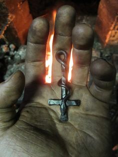 a person holding a cross in their hand with flames coming out of the back ground behind them