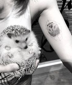 a woman holding a small hedgehog in her hands with a tattoo on it's arm