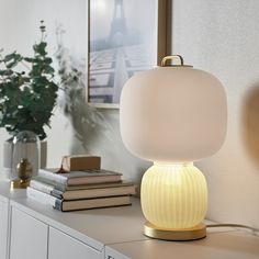 a white lamp sitting on top of a table next to a vase with flowers in it