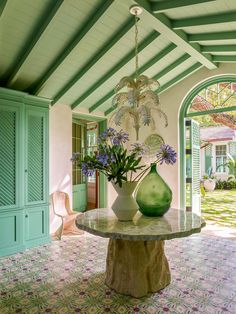 two vases filled with flowers sit on a table in the middle of a room