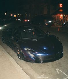 a black and blue sports car parked on the side of the road at night time