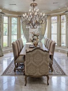 an elegant dining room with chandelier and large table in front of two windows