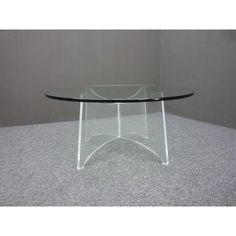 a glass table sitting on top of a carpeted floor next to a gray wall