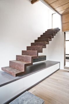 a set of stairs in the middle of a room with wooden floors and white walls