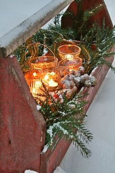 candles are lit on the ledge outside in the snow