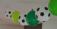 soccer balls hanging from the ceiling with green and white balloons