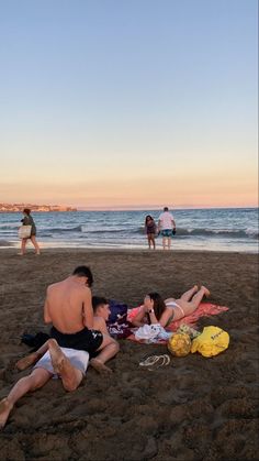 some people are laying on the sand at the beach