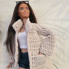 a doll is wearing a crocheted jacket and shorts with her hands on her hips