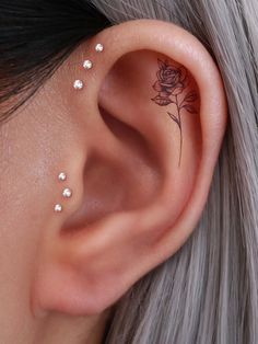 a close up of a person's ear with a rose tattoo on the side