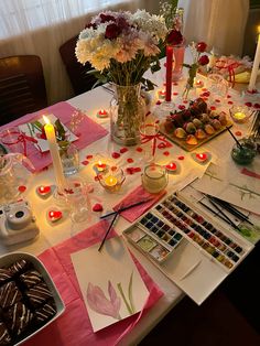 a table is set with candles, flowers and other items for an art class or party