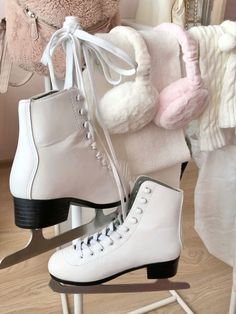 two white ice skates sitting on top of a wooden floor next to a teddy bear