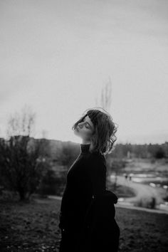 a black and white photo of a woman looking up at the sky with her eyes closed