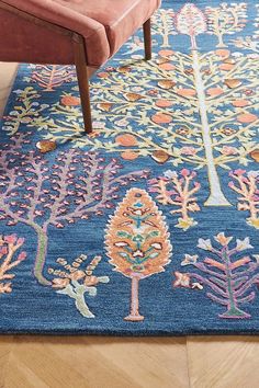 a blue rug with colorful trees on it and a bench in the corner next to it