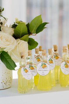 several bottles of lemonade sit on a table with white flowers and greenery in the background