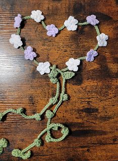 crocheted flowers are arranged in the shape of a heart on a wooden table