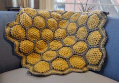 a crocheted yellow and gray blanket sitting on top of a blue couch next to a window