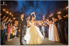 a bride and groom holding sparklers in front of their wedding party