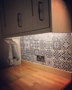 the kitchen counter is covered with black and white tile backsplashes, along with wooden flooring