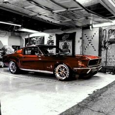 an old mustang car is parked in a garage with graffiti on the walls and floor