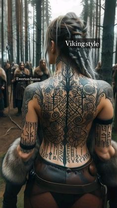 a woman with tattoos on her back in the woods