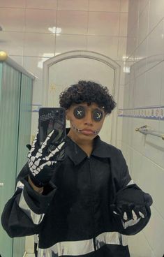 a person in a bathroom holding up a cell phone with skeleton hands on it's face