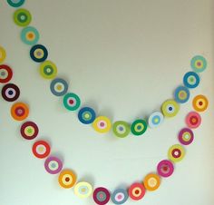 a multicolored paper circle garland hanging from a white wall in a room with an open door