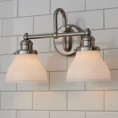 two light bathroom fixture with frosted glass shades on white tile backsplashing