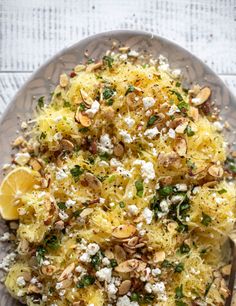 a white plate topped with pasta covered in feta cheese and almonds next to a fork