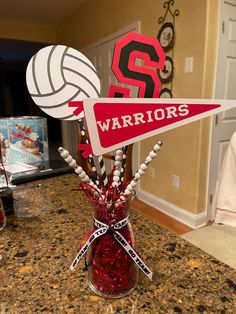 a vase filled with candy and sports themed items on top of a countertop next to a volleyball ball