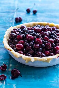 a pie crust filled with berries on top of a blue table