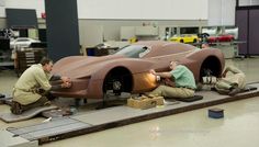 three men working on a car in a garage