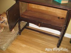 a brown dog sitting under a desk on top of a hard wood floor