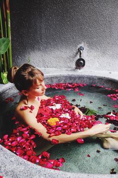 a woman sitting in a bath filled with petals