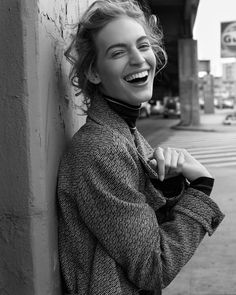 a woman leaning against a wall and smiling