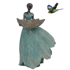 a statue of a woman holding a leaf with a bird flying nearby