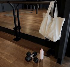 a white tote bag sitting on top of a wooden floor next to dumbs