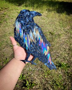 a hand is holding a paper bird in the grass